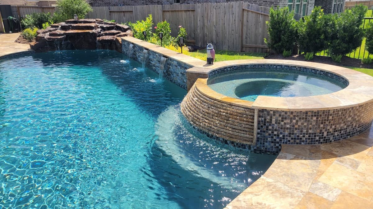 Custom backyard pool with water feature and travertine decking