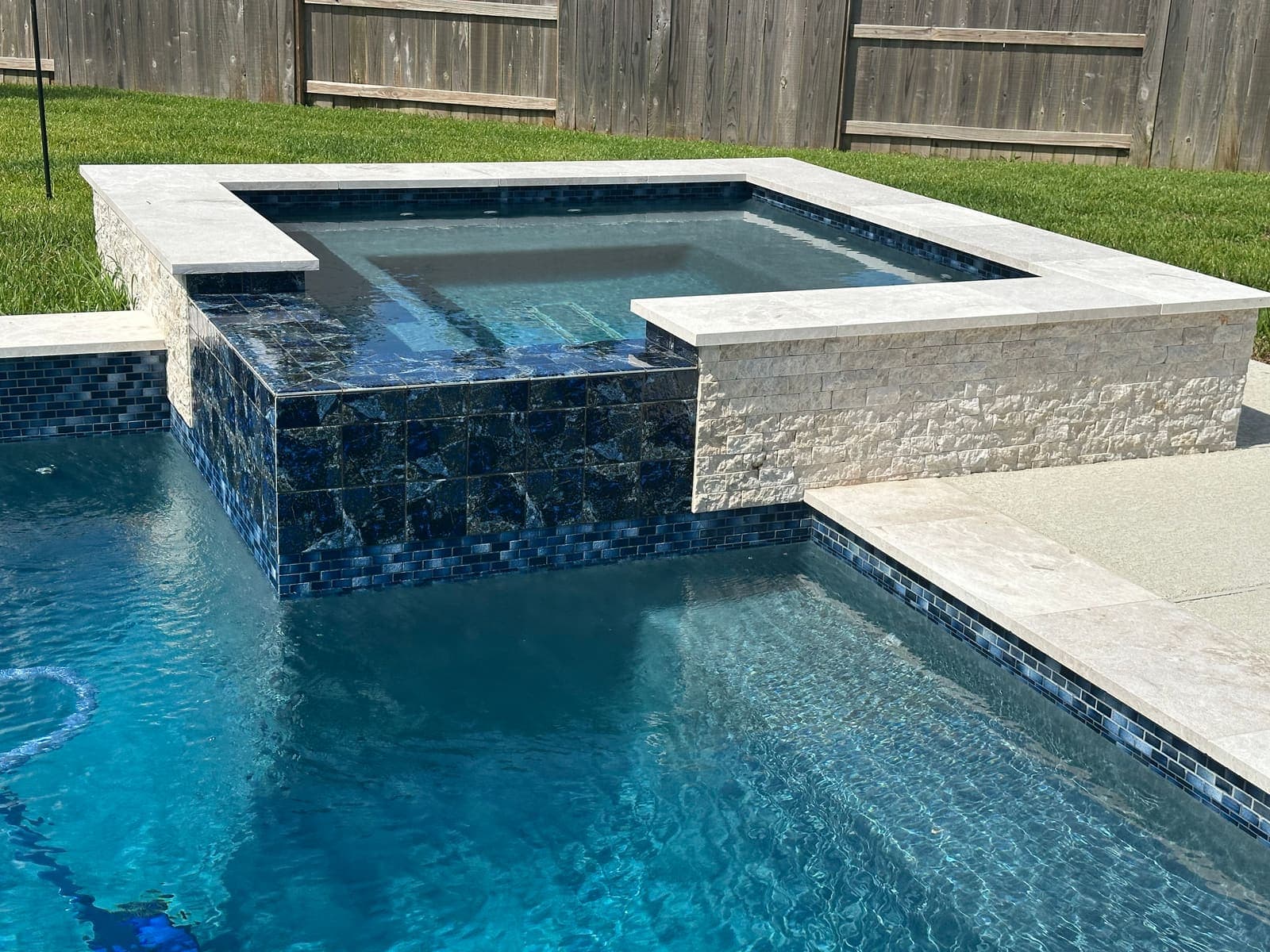 Pool with tanning ledge in a landscaped backyard
