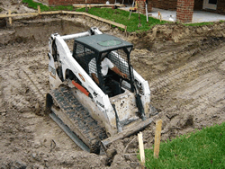 Bobcat tractor excavating the pool cavity to the staked-out shape