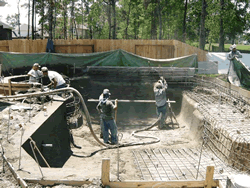 Crew pneumatically spraying gunite to form the pool shell over the rebar