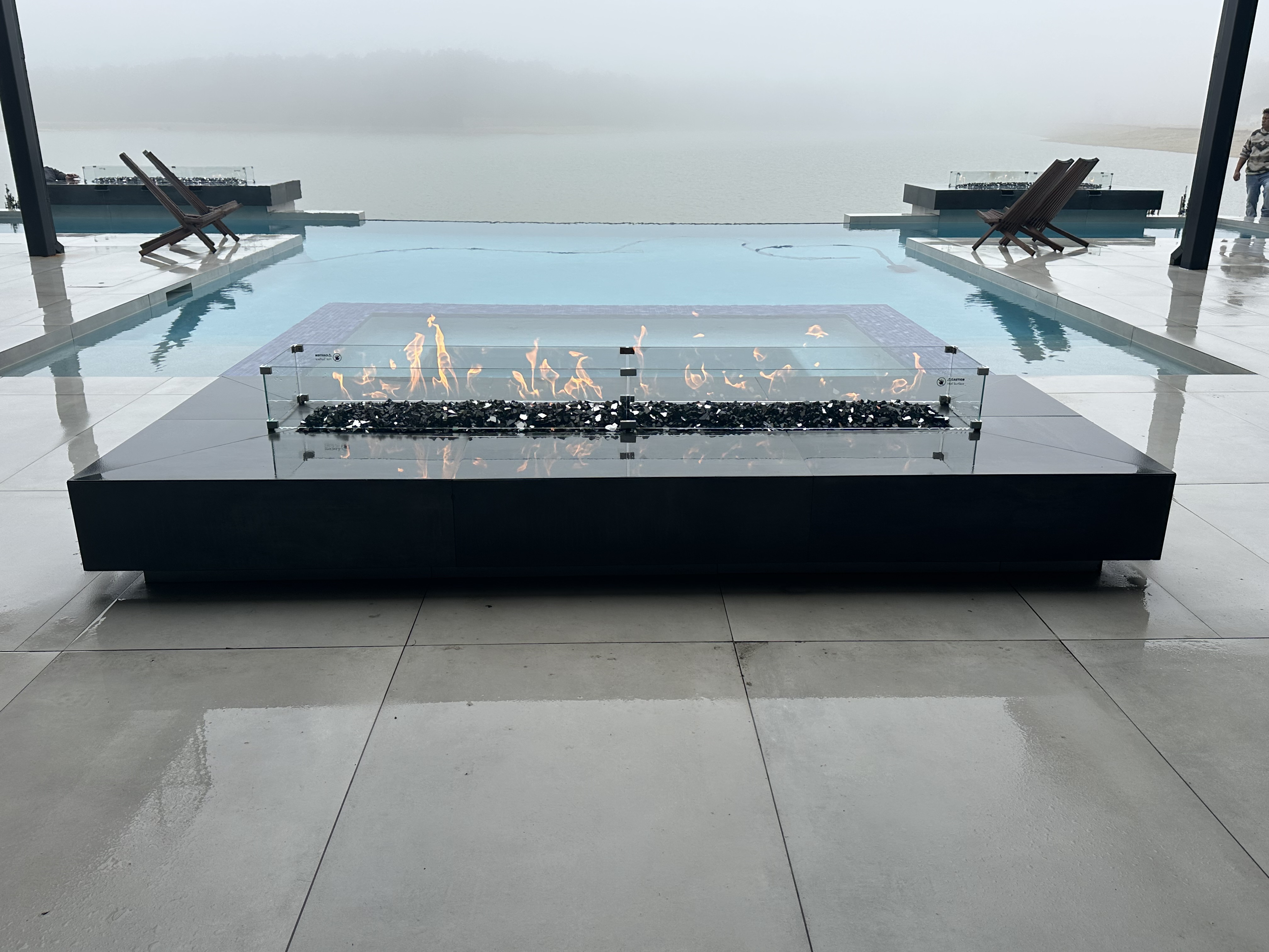 Fire pit by Houston Cool Pools - glass-enclosed fire pit on a pool deck