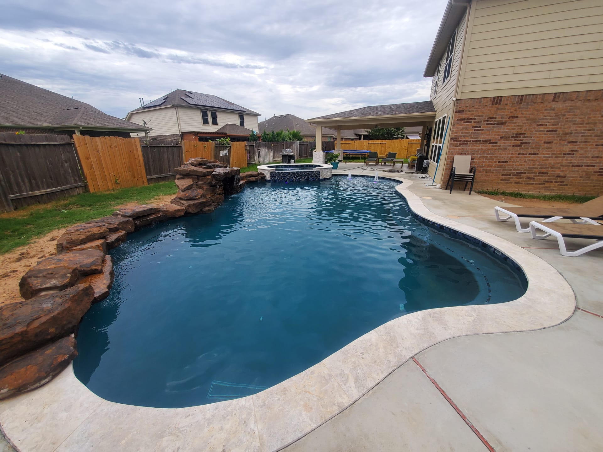 Free form pool by Houston Cool Pools - free-form pool with rock waterfall grotto and raised spa