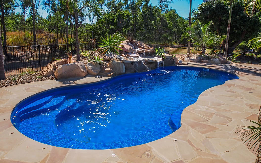 Free form pool by Houston Cool Pools - kidney-shaped pool with natural rock waterfall grotto