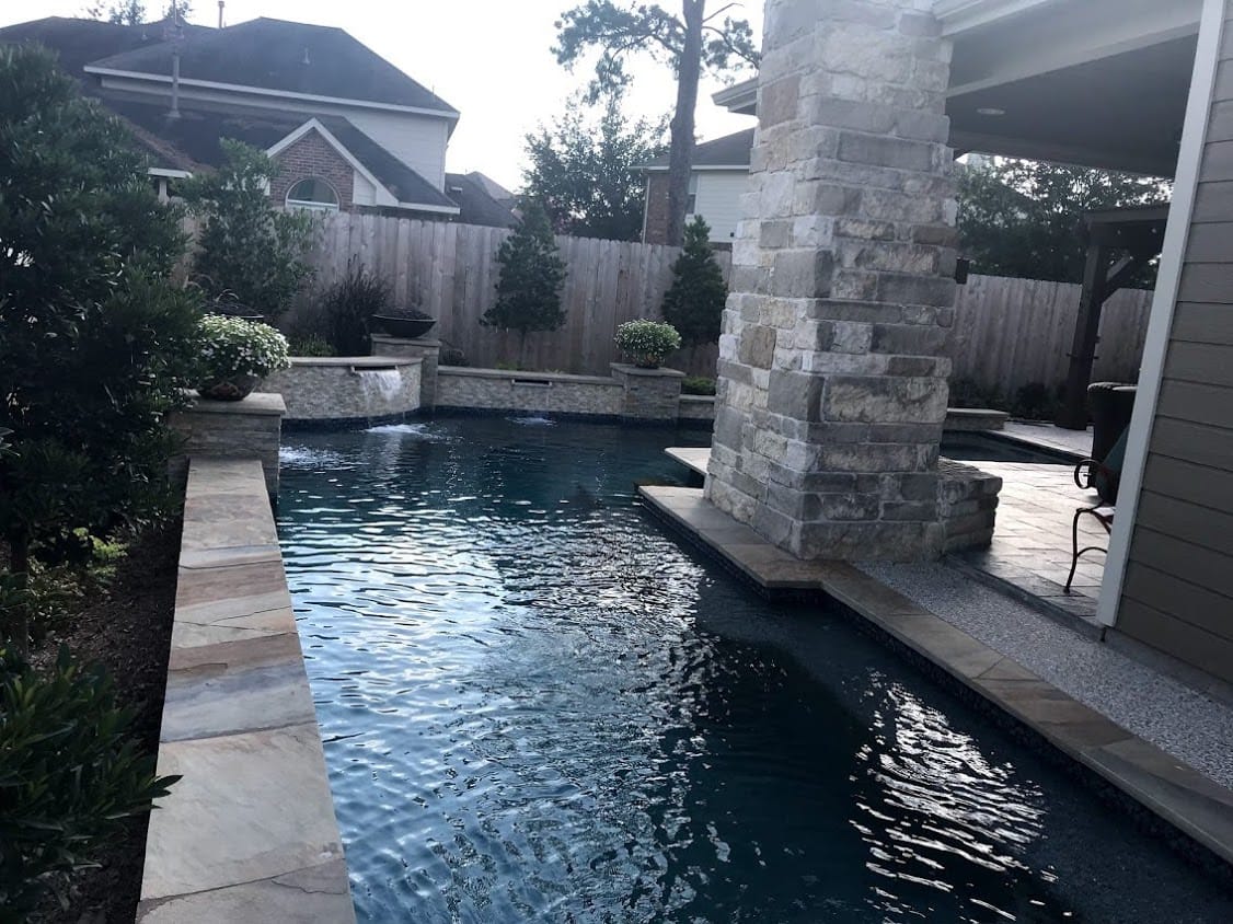 Free form pool by Houston Cool Pools - curved cove pool with raised spa and stone column