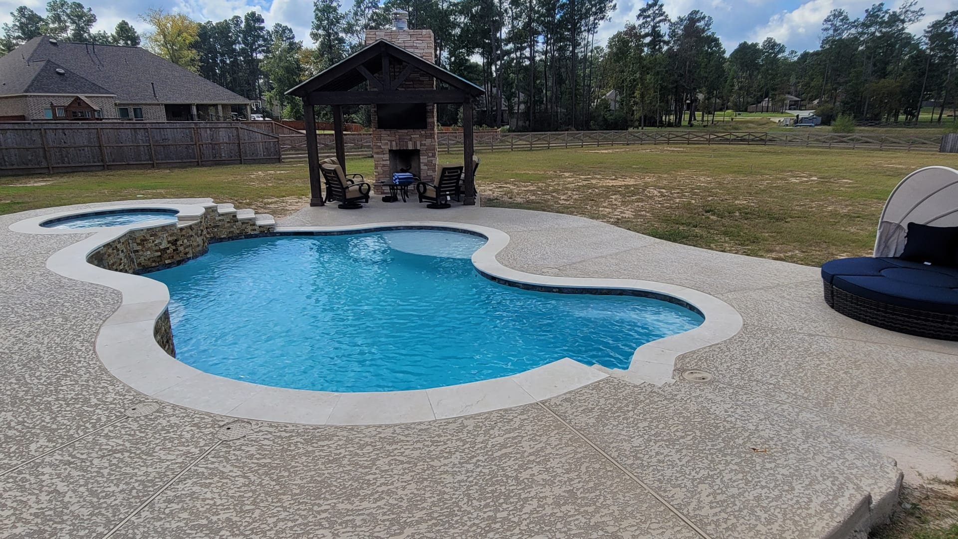 Free form pool by Houston Cool Pools - organic lagoon-shaped pool with covered fireplace patio