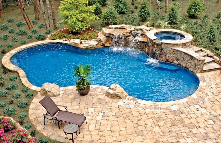 Free form pool by Houston Cool Pools - kidney-shaped pool with rock waterfall and raised spa