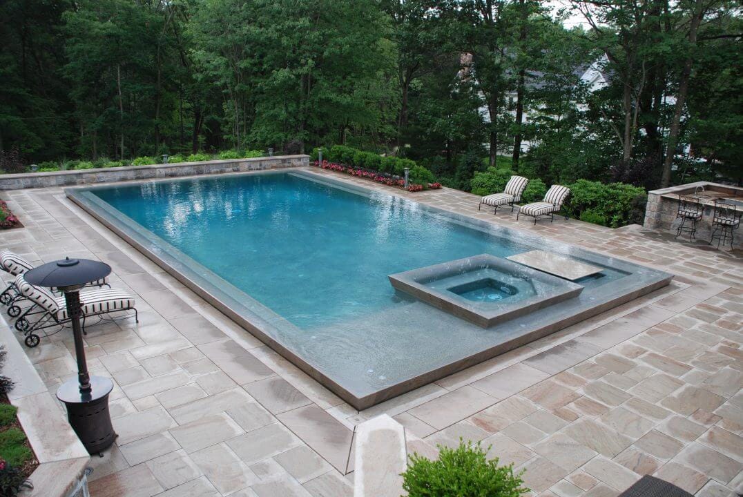 Geometric pool by Houston Cool Pools - rectangular pool with raised spa and stone patio