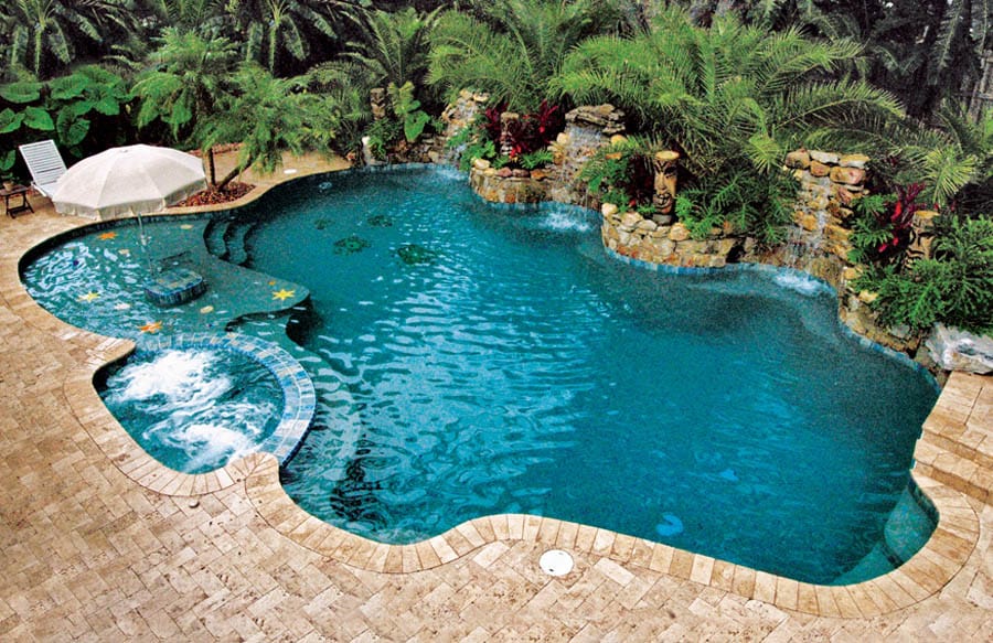 Free form pool by Houston Cool Pools - tropical lagoon pool with tiki-carved rock wall and spa